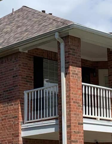 New seamless aluminum gutter and downspout installed along the edge of a Texas home