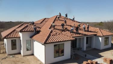 Professional crew installing terracotta clay tile on a Texas home roof