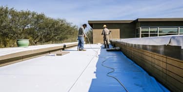 Roofing crew installing white TPO membrane on a commercial flat roof in Texas