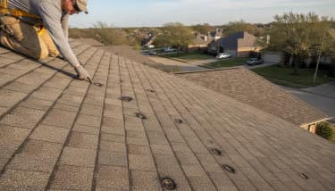 Roof inspector pointing out hail damage bruises and dents on an asphalt shingle roof